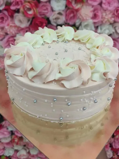 A customized blueberry cake with delicate pink frosting and silver pearl details. I can adapt any flavor to your design preferences.