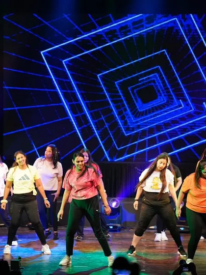 The entire group of ladies filling the stage with color and energy during their Zumba performance at Zest '25.