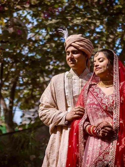 A sun-dappled portrait of the couple in a garden setting. The natural light filtering through the trees adds a soft, romantic quality to the image.