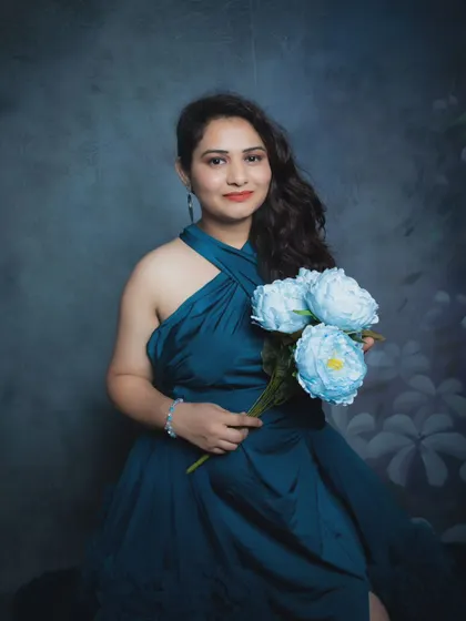 A lovely seated portrait of a woman in a blue gown holding a bouquet of matching flowers.