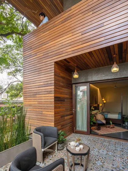 A cozy balcony off a bedroom, offering a private outdoor space to enjoy a cup of tea while being surrounded by the home's wooden facade and greenery.