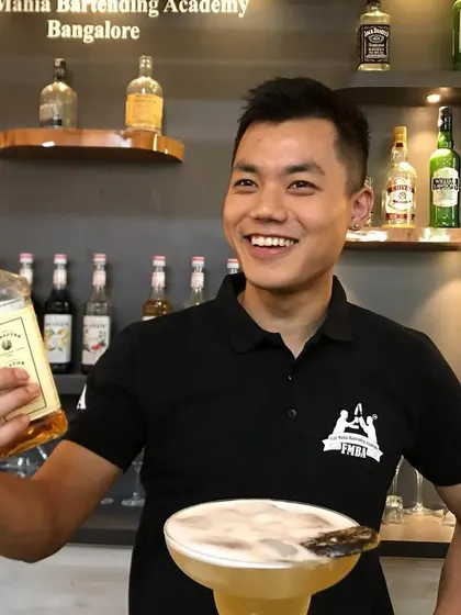 A happy bartender from our Bangalore academy, showcasing his latest cocktail creation with a smile.