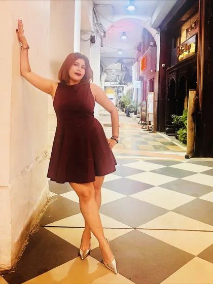 A more playful pose in the same birthday dress, leaning against a wall to show the dress's movement and fit.