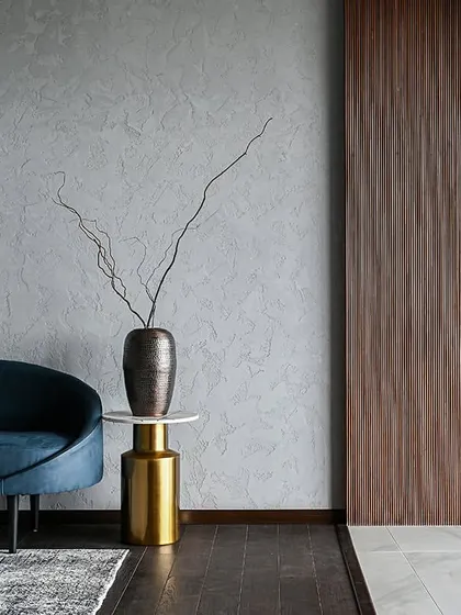 A detail shot focusing on the interplay of textures: the smooth curve of the sofa, the rough texture of the vase, and the vertical grain of the wood paneling.