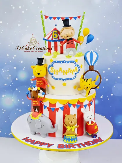 Step right up to this amazing two-tier circus cake for Shanaya's 6th birthday. It's full of fun, with a ringmaster, acrobatic animals, and a classic red-and-white striped tent.