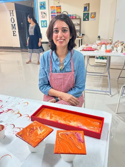 A guest with her finished fluid art tray and coaster set in beautiful shades of orange.