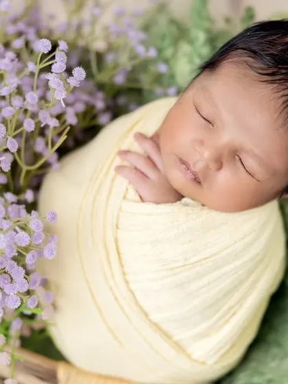A close-up on the baby's peaceful face, surrounded by the delicate purple flowers. These shots are perfect for highlighting your newborn's serene beauty.