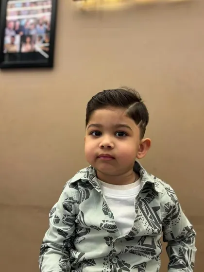 A frontal view of a cute little boy with his new, sharp haircut, looking very dapper.
