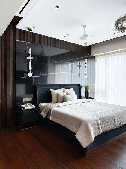This luxury master bedroom features opulent wooden finishes and a striking black book-matched marble backsplash. The wooden fluted paneling cleverly hides the walk-in wardrobe door.
