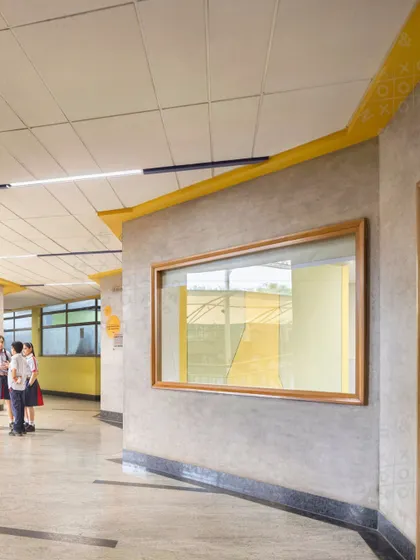 A corridor at GD Goenka Public School, Vasant Kunj, with a large window looking out onto the playground. The design connects the interior with the outdoors and uses color to enrich the students' daily experience.