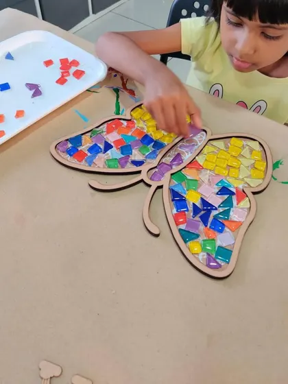 Look at the focus and creativity! This is what it's all about, a hands-on activity where kids can get lost in making something beautiful, like this colorful butterfly mosaic.