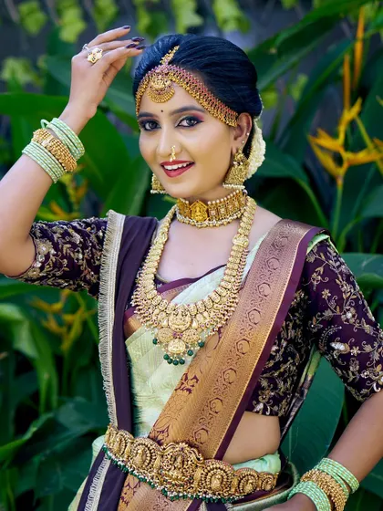 This bride is radiant in a light green and maroon silk saree. The makeup is kept fresh and glowing to complement the unique colour combination and antique gold jewellery.