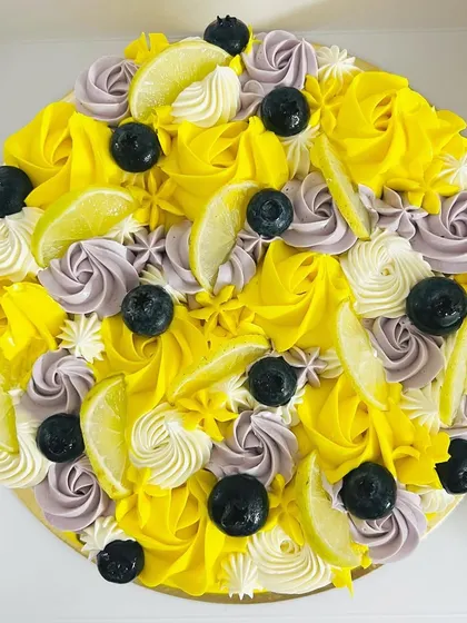 A burst of summer flavor. This Lemon Blueberry cake is decorated with swirls of yellow and lavender buttercream, fresh blueberries, and lemon slices. It's as bright and zesty as it looks.