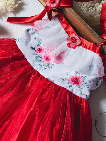 A stunning combination of red and white. This party dress features a floral embroidered bodice, a full red tulle skirt, and elegant satin straps with floral details.