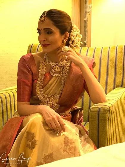 A portfolio shot showcasing a classic muhurtham look. The combination of a beige and red saree with traditional jewelry and a red lip is timeless.