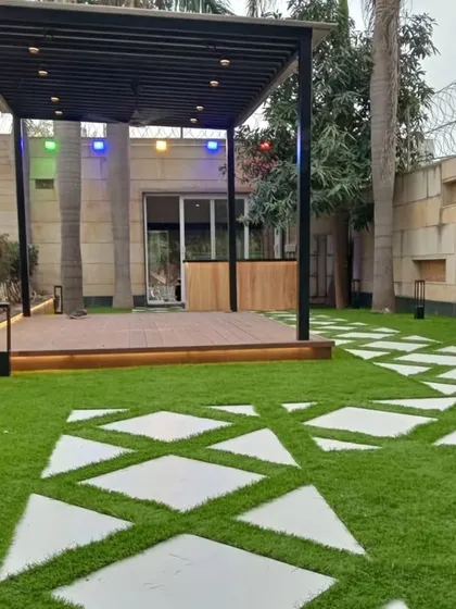 A view down the geometric pathway in the Dwarka project, leading towards the pergola and a separate bar area.