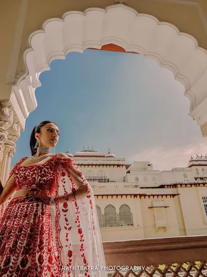 A low-angle shot of the bride looking powerful and regal, framed by a palace archway.