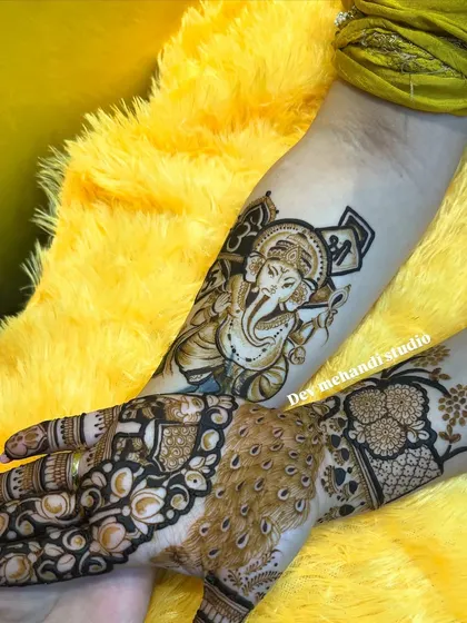 A powerful portrait of Lord Ganesha on the forearm, paired with a peacock feather design on the hand. This shows how we can combine different elements into one cohesive piece.