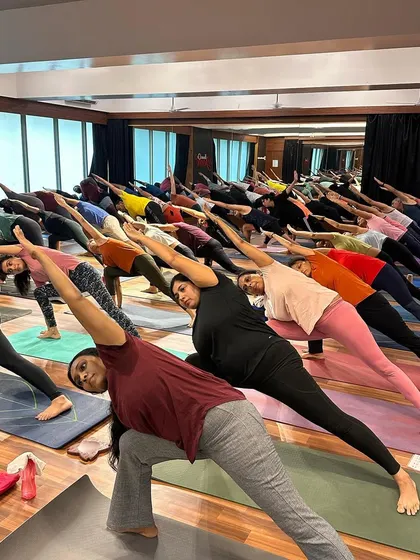 Students in Utthita Parsvakonasana during a large community class. The synchronized movement creates a powerful wave of energy.