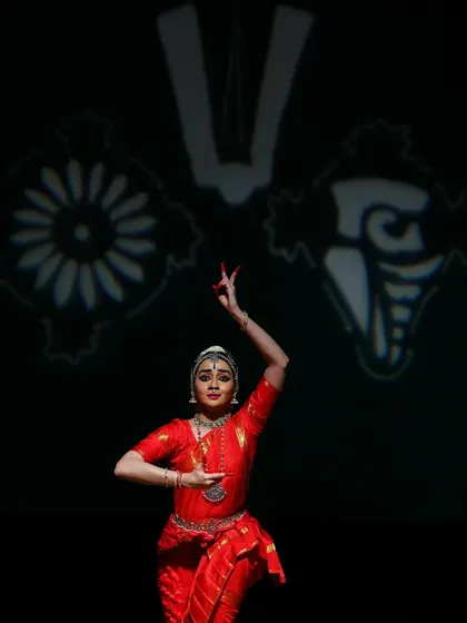 A pose in front of the projected symbols of Lord Venkateshwara, the Shankha and Chakra. This staging element helps transport the audience to the sacred space of Tirumala.
