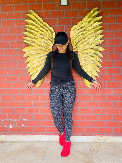 Find your wings at Switch. A member poses with our iconic golden wings mural, a favorite spot for a post-workout photo.