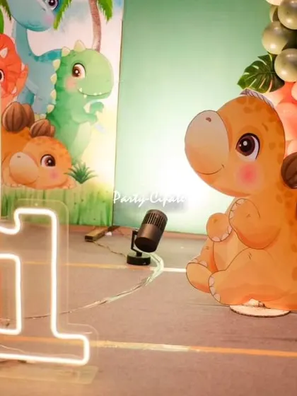 Details are everything. This shot highlights the light-up number '1' and a cute stegosaurus cutout, adding a warm glow and character to the dinosaur theme.