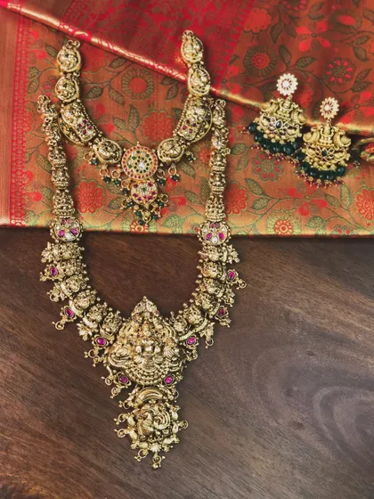 A full temple jewellery set with a choker and a long haram, laid out against a silk saree. This shows how beautifully the jewellery complements traditional attire.