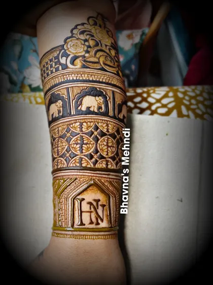 A close up of a beautiful arm band design. This piece features elephants, geometric patterns, and the couple's initials 'HN'.