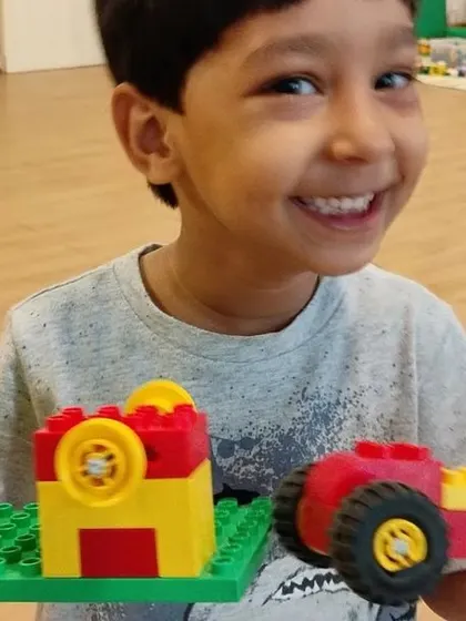 A smiling camper shows off the tractor and trailer he built, a fun project for our younger engineers.