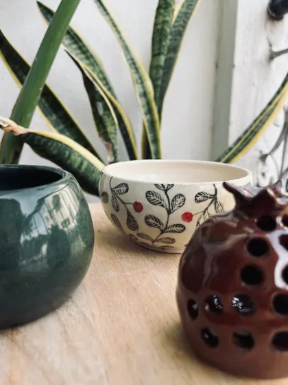 A collection of student pieces, including a sgraffito bowl and a pomegranate-shaped luminary. The variety of styles is always amazing to see.