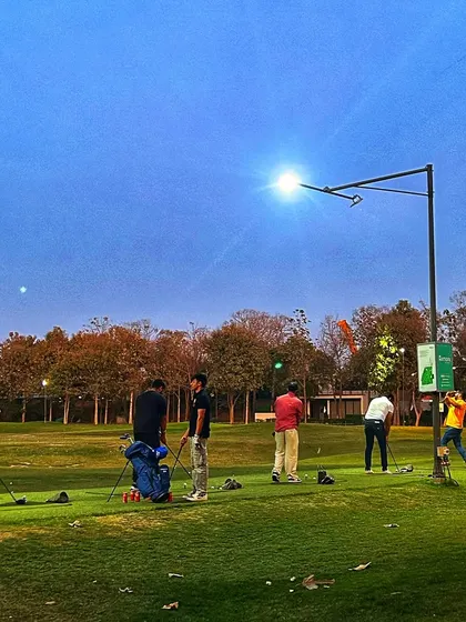 The range under the lights as dusk settles, with a clear blue sky above.
