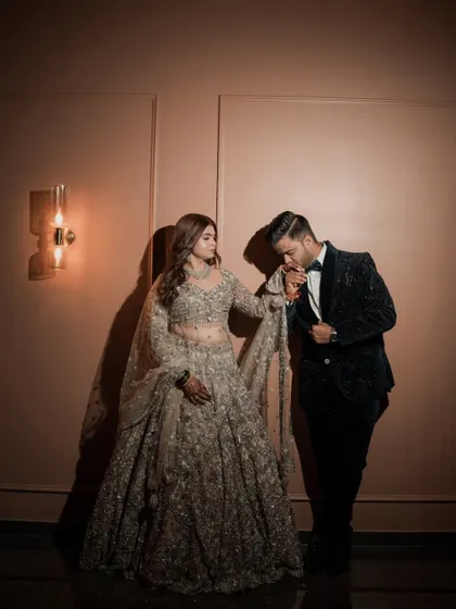 A chivalrous moment captured beautifully. The groom kisses his bride's hand, and her glamorous reception makeup looks absolutely perfect in the warm, dramatic lighting.