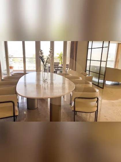 The formal dining area at our Prestige White Meadows project. An elegant oval marble table is surrounded by contemporary chairs, all set against a backdrop of large windows that flood the space with natural light.