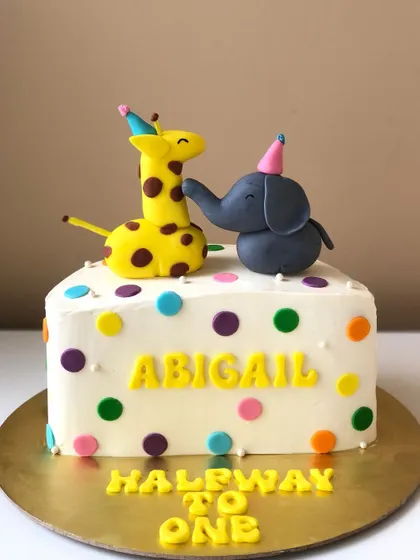 A "Halfway to One" cake with adorable giraffe and elephant friends celebrating together.
