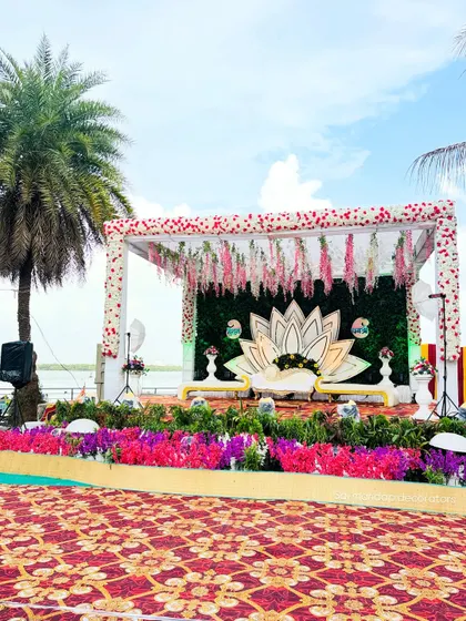 This is a beautiful outdoor engagement stage I created with a lotus theme. This setup by the water in Navi Mumbai includes a custom lotus backdrop, a lush green wall, and hanging floral arrangements, perfect for a memorable ring ceremony.