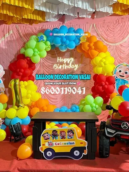 A Cocomelon theme with a toy car prop for the birthday boy. The bright, primary-colored balloons and character cutouts create a playful atmosphere.