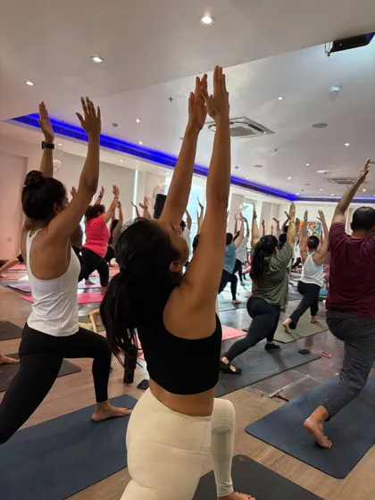 The energy of a full room moving together in Virabhadrasana I (Warrior I). This image captures the collective power and spirit of our community.
