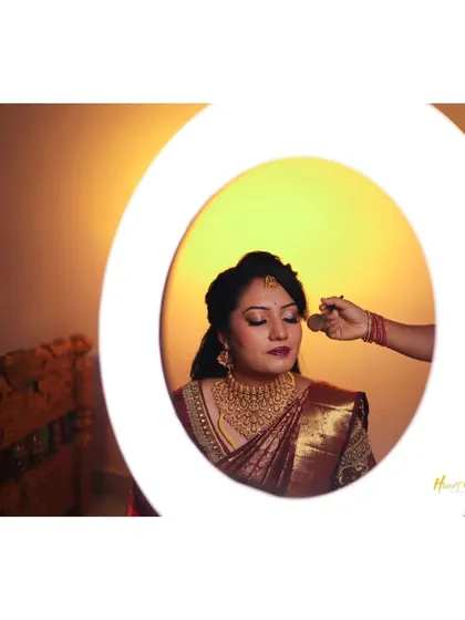 A creative shot of the bride getting her makeup done, viewed through the circle of a ring light.