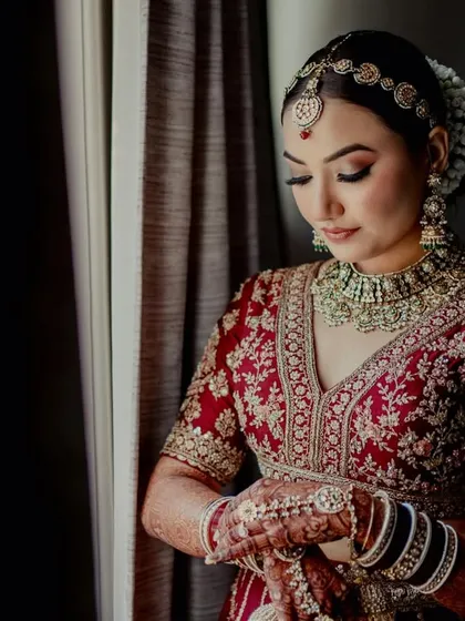 A quiet moment of reflection. The bride's makeup is soft and elegant, with a beautifully done bun and gajra, perfect for her traditional look.
