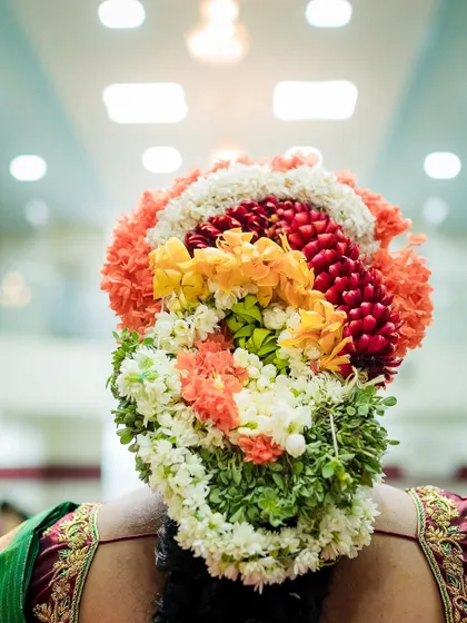 The intricate and colorful floral arrangement in the bride's hair, a beautiful tradition in South Indian weddings that we love to photograph.