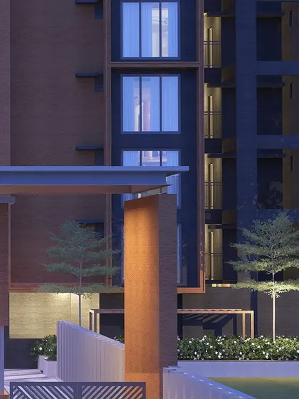 A close-up of an architectural corner at night, where uplighting on a textured pillar and the warm glow from windows create a composition of light, shadow, and material.
