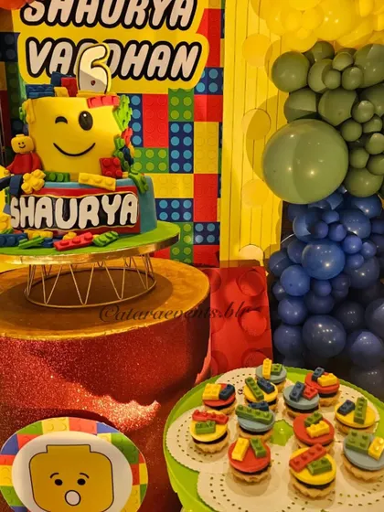 The dessert table is a feast for the eyes, featuring a LEGO-themed cake and cupcakes with brick toppers, all perfectly matching the colorful decor.