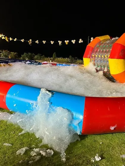 A full foam party setup showing the inflatable pool filled with foam. You can see a water zorbing roller in the background, showing how activities can be combined.