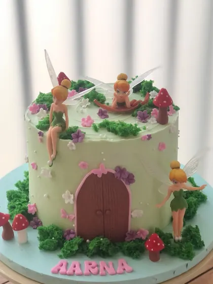 A magical Tinker Bell cake, creating a fairy house scene with buttercream moss, toadstools, and tiny fairies.