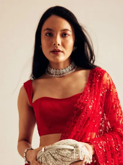 A serene portrait in the red saree. The makeup is clean with a focus on the lips, and the hair is styled to fall naturally, creating a look of effortless sophistication.