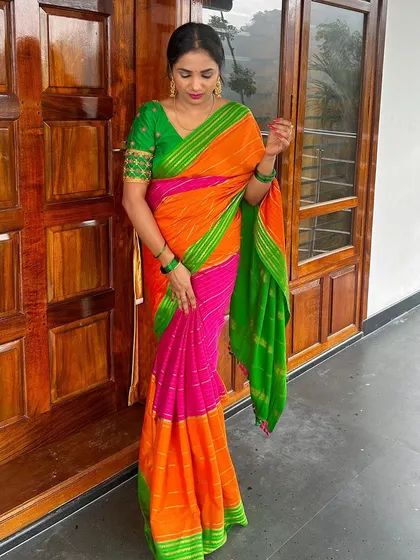 A client looking lovely in a bright, multi-colored saree. The custom green blouse with simple sleeve embroidery provides a perfect pop of contrast.