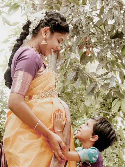 The bond between a mother and child is precious. Here, an older sibling-to-be lovingly touches his mother's baby bump in a beautiful, sunlit outdoor setting.