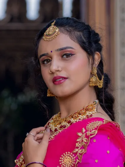 A portrait shot focusing on the ruby and gold jewellery set, including the necklace, maang tikka, and nose ring.