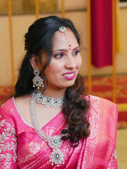 A perfect look for a reception or sangeet. This bride is wearing a bright pink saree with stunning diamond and emerald jewellery, and her makeup is glamorous with a pop of pink on the lips.