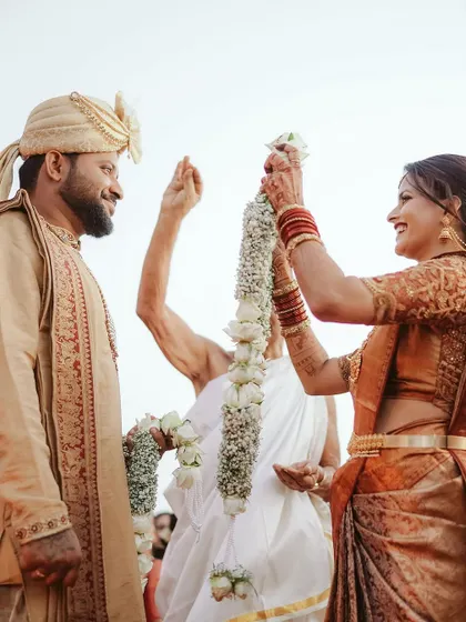 The garland exchange is a pivotal moment in any Indian wedding. Here, at a beautiful Mangalorean beach wedding, the couple exchanges vows against the serene backdrop of the setting sun.